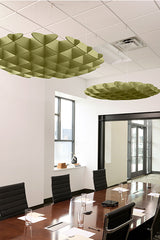 Green 3D foil cloud baffles suspended from white drop ceiling above conference table with black chairs.
