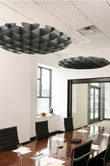 Black 3D cloud-shaped ceiling baffles suspended above conference table in office space.