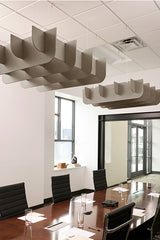 Wavy acoustic baffles suspended from drop ceiling above conference table in modern office space.