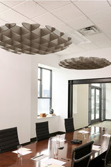 Two metallic 3D cloud-shaped ceiling baffles suspended above a conference table in an office space.