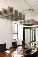 Beige acoustic baffles with geometric grid pattern suspended from ceiling above conference table in office.