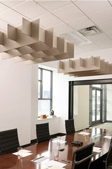 Beige geometric acoustic baffles suspended from ceiling in modern office conference room with meeting table.