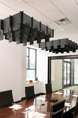 Black modular acoustic baffles suspended from ceiling in office conference room above wooden table.