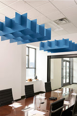 Blue geometric cloud-shaped acoustic baffles suspended from drop ceiling in office conference room.