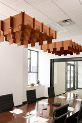 Terracotta 3D modular ceiling baffles with geometric cutouts suspended above conference table in office.