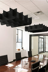 Black 3D cloud-shaped acoustic baffles suspended from drop ceiling above conference table.