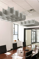White cloud-shaped acoustic baffles suspended from ceiling above conference table in modern office.