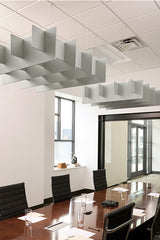 Gray grid-pattern acoustic baffles suspended from ceiling above conference table in office space.