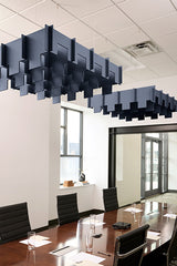 Two dark blue 3D cloud-shaped acoustic baffles suspended from drop ceiling in office conference room.