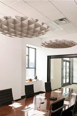 Two beige 3D cloud-shaped acoustic baffles suspended from a drop ceiling in a modern office conference room.
