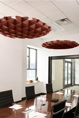 Two burgundy 3D cloud-shaped acoustic baffles suspended from a white drop ceiling in a modern office conference room.