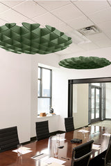 Green 3D cloud-shaped acoustic baffles suspended from white ceiling above conference table.