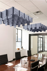Blue-grey modular acoustic panels suspended from ceiling in staggered 3D formation above conference table.