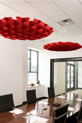 Red foil 3D cloud-shaped acoustic baffles suspended from white ceiling in modern office conference room.