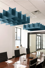 Blue geometric acoustic baffles suspended from white drop ceiling above conference table.