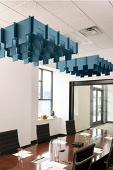 Blue 3D cloud-shaped acoustic baffles suspended from ceiling in office conference room above wooden table.