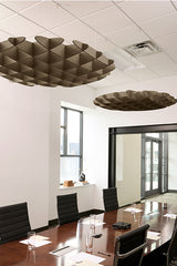 Two metallic 3D cloud-shaped ceiling baffles suspended above a conference table in an office space.