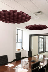 Two burgundy 3D cloud-shaped acoustic baffles suspended from a drop ceiling above a conference table.