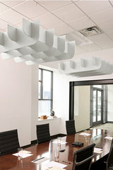 White curved acoustic baffles suspended from drop ceiling above conference table in office space.