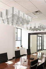 White 3D modular cloud-shaped acoustic baffle suspended from ceiling above conference table.