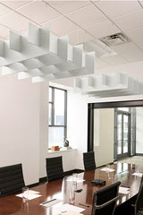 White modular acoustic baffles suspended from ceiling above conference table in office space.