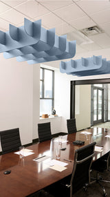 Blue wavy acoustic baffles suspended from ceiling above conference table in office space.