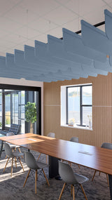 Blue curved acoustic panels suspended from ceiling in office conference room above wooden table.
