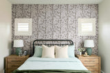 Bedroom with floral wallpaper, wooden nightstands, and lamps.