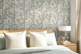 Bedroom with floral-patterned wallpaper, bed with pillows, and nightstand with lamp.