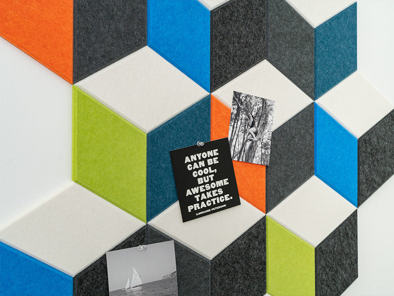 A Felt Right wall geometric art design in grey, blue, green, orange, and cream felt tiles forming a 3d like cube design with some photos pinned to the tiles