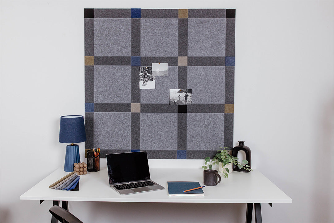 Pinnable Felt Right sound absorbing pinboard in a colorway that encourages focus. It has greys, blues, and neutrals. This pinboard is located behind a white desk with a computer on the desktop.