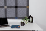 Pinnable Felt Right sound absorbing pinboard in a colorway that encourages focus. It has greys, blues, and neutrals. This pinboard is located behind a white desk with a computer on the desktop.