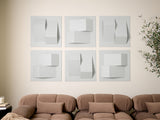 Six white three-dimensional geometric tiles with layered rectangular and curved forms arranged in a grid on a wall.