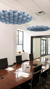 Blue 3D cloud-shaped acoustic baffles suspended from ceiling in conference room setting.