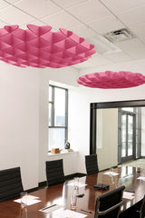 Pink 3D cloud-shaped ceiling baffles with geometric folded pattern suspended in office conference room.