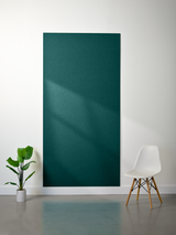 Teal-colored 9mm felt sheet displayed on white wall with plant and chair.