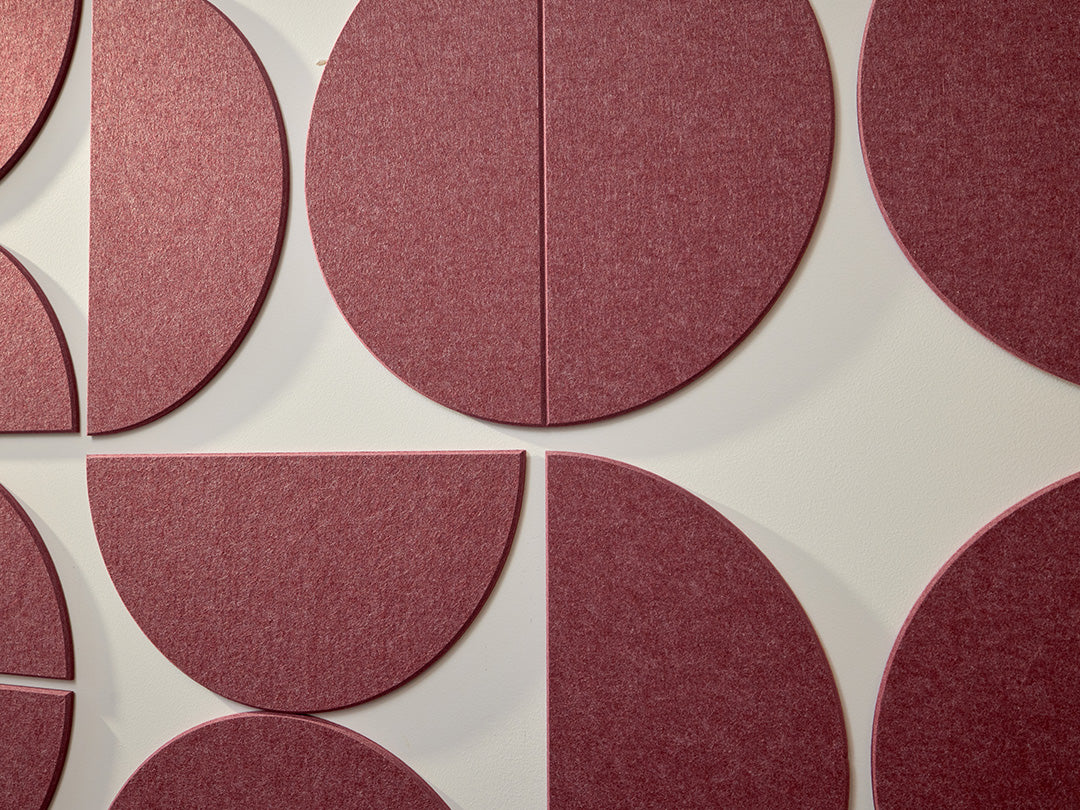 A Felt Right wall art design using large half circles to form a geometric pattern in a dark red shade on a white wall.