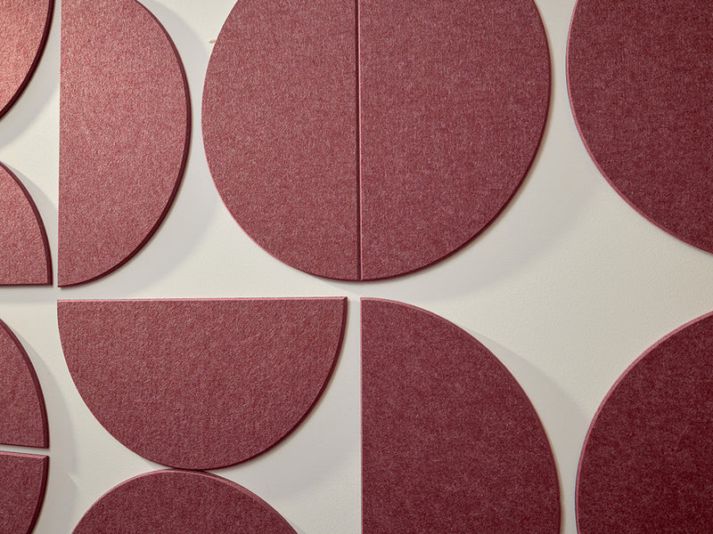 A Felt Right wall art design using large half circles to form a geometric pattern in a dark red shade on a white wall.