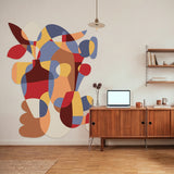Large felt wall mural in primary colors on a white wall next to a table with laptop. 