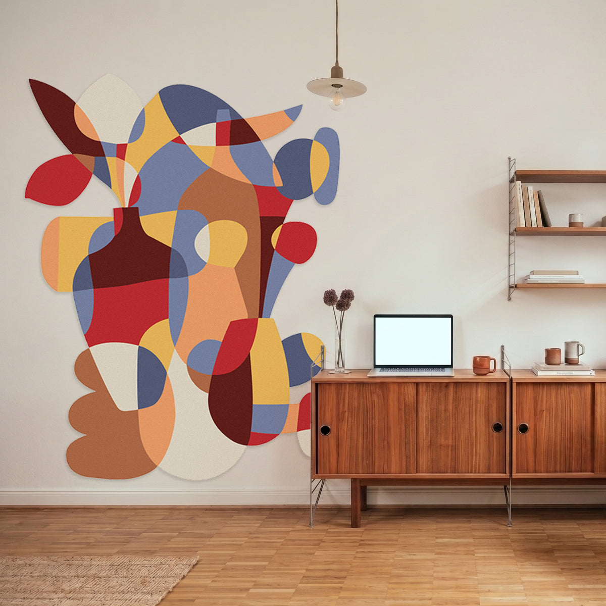 Large felt wall mural in primary colors on a white wall next to a table with laptop. 