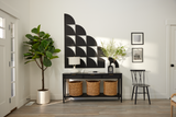 A Felt Right wall art design using black quarter circles to create a geometric slope pattern on a white wall at the entry of a home above a table with decor and a house plant in the corner.