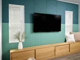 Modern living room with a television mounted on a teal wall, wooden cabinet, and decorative elements.