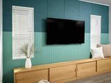 Modern living room with a television mounted on a teal wall, wooden cabinet, and decorative elements.