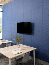 Modern office space with a blue paneled wall, TV, and desk setup.