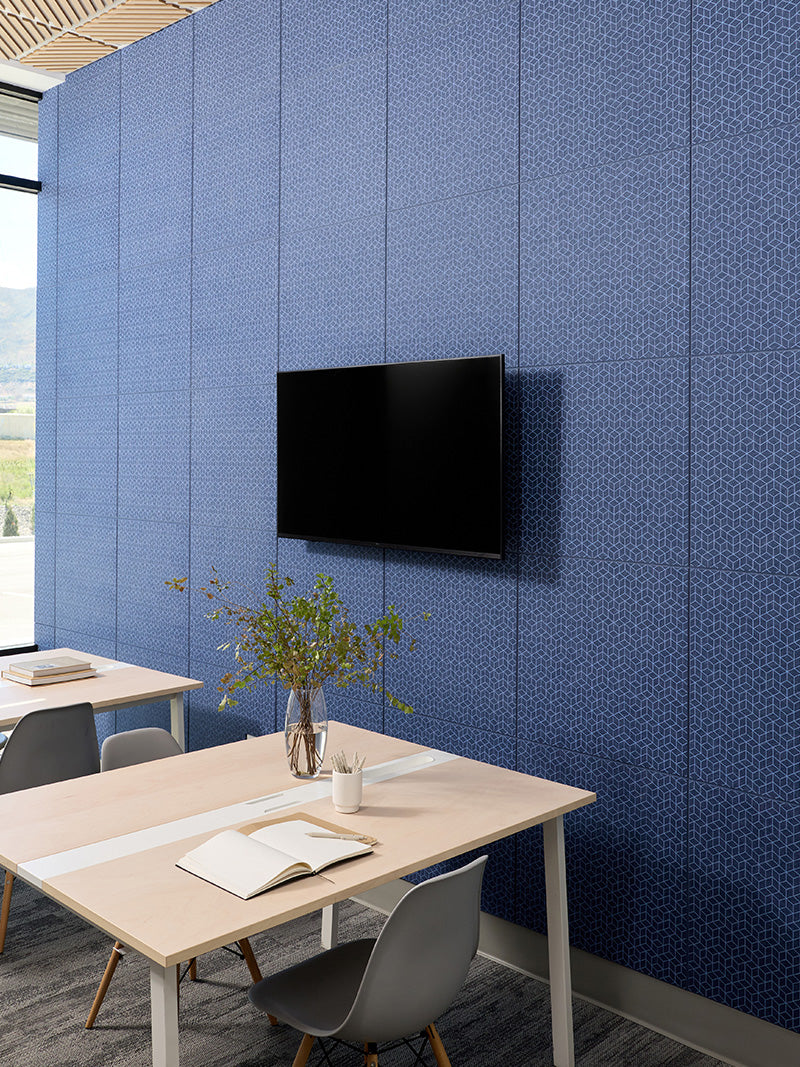 Modern office space with a blue paneled wall, TV, and desk setup.