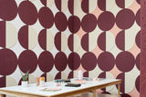 A Felt Right wall art design in shades of pink purple and cream circle tiles creating geometric pattern on a wall corner with a craft table.