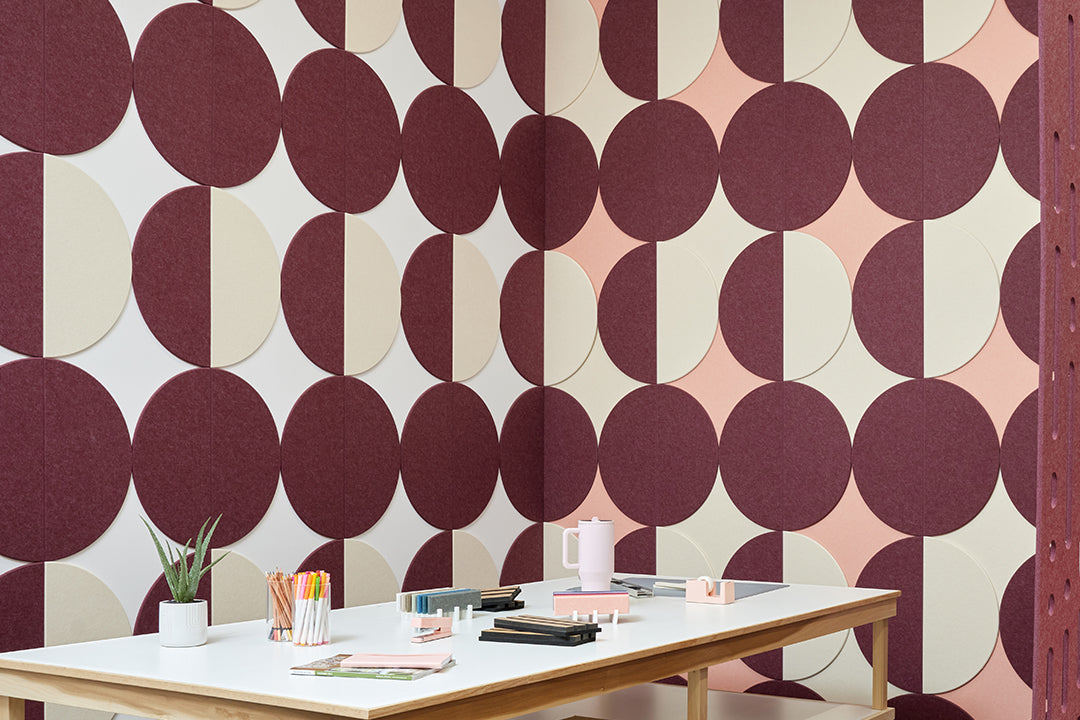 A Felt Right wall art design in shades of pink purple and cream circle tiles creating geometric pattern on a wall corner with a craft table 