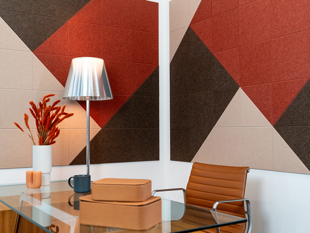 Felt Right wall art design in shades of brown, cream, and red patterned on two walls in an office by a desk and a lamp in the corner.