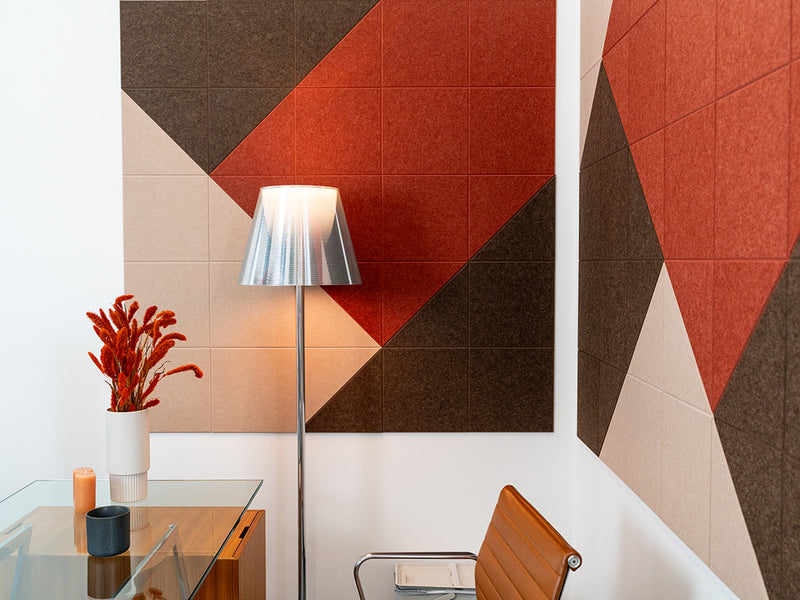 Felt Right wall art design in shades of brown, cream, and red patterned on two walls in an office by a desk and a lamp in the corner.