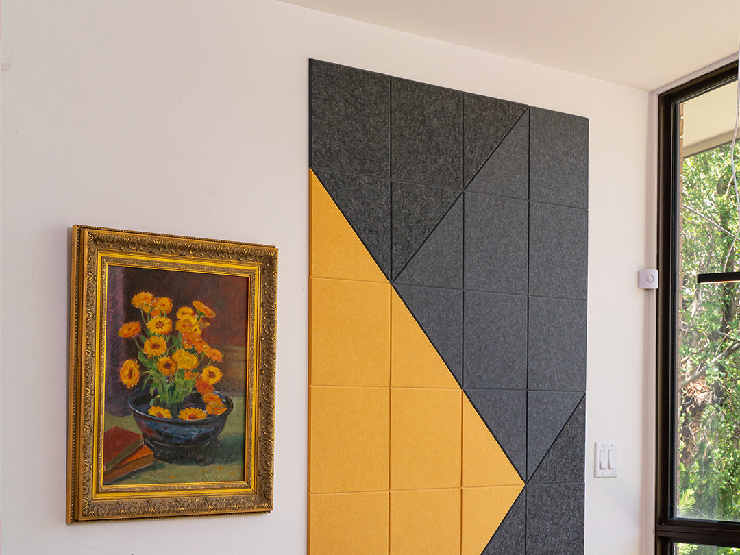 Felt Right wall art design in shades of yeloow and black felt tiles on a white wall next to a painting and a window